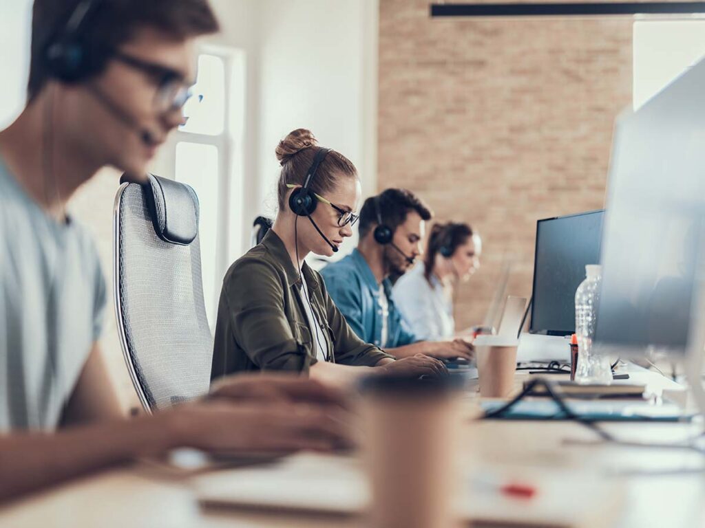 Kundenservice-Team im Callcenter arbeitet konzentriert am Computer, trägt Headsets für optimale Kommunikation und Support.