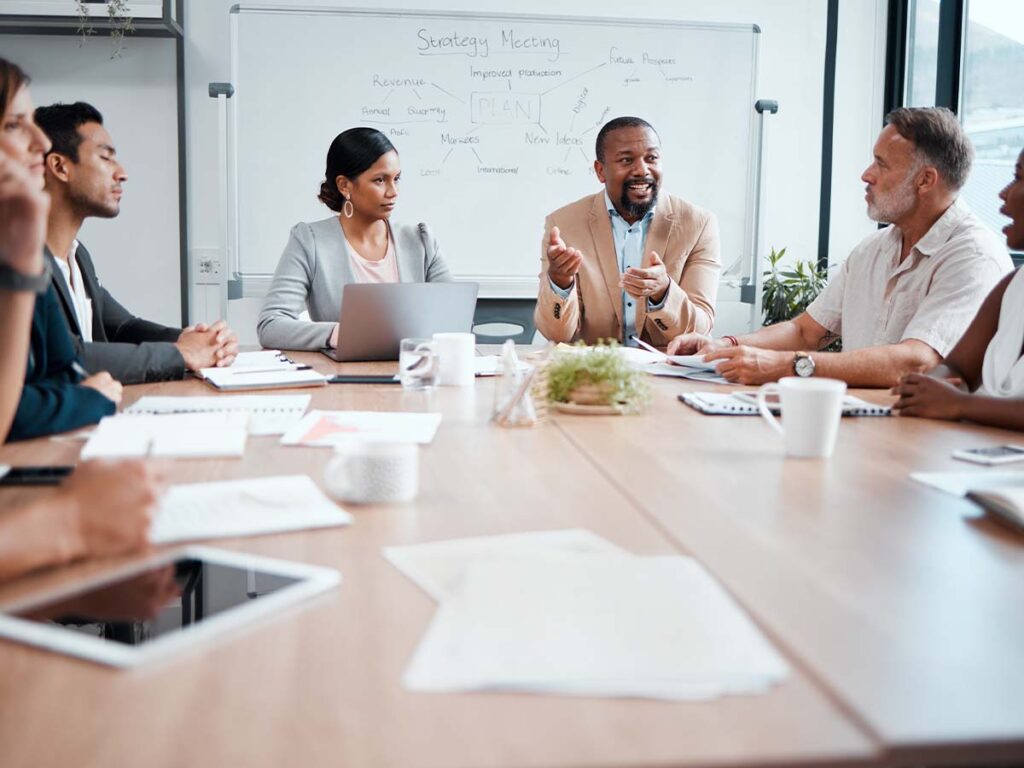 Geschäftsmenschen in Sitzung diskutieren Unternehmensstrategien am Konferenztisch. Teamarbeit, Planung, Büro, Meeting.