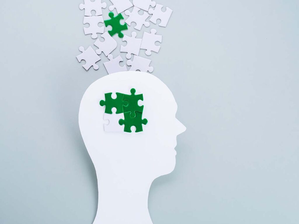 Silhouette eines Kopfes mit Puzzle-Teilen, die Gedanken symbolisieren. Keywords: Geist, Denken, kognitive Prozesse.