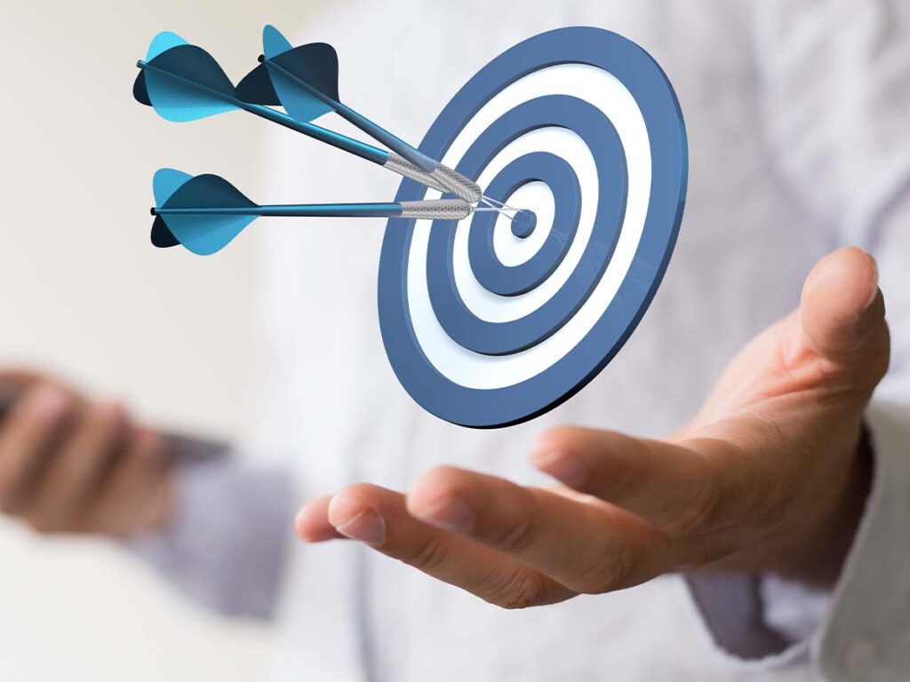 Hand hält Zielscheibe mit drei Pfeilen, Konzept für Zielerreichung und Fokus in der Geschäftswelt.