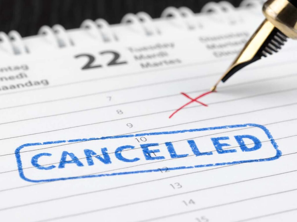 Kalenderseite mit rotem X auf dem 22. und blauem „CANCELLED“-Stempel. Planung und Terminabsage im Fokus.