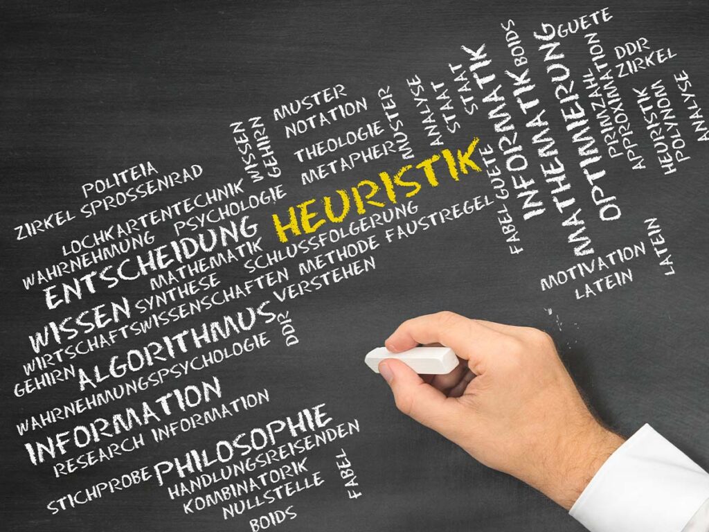 Tafel mit Begriffen wie Heuristik, Entscheidung und Algorithmus wird von Hand mit einem Radiergummi geändert.