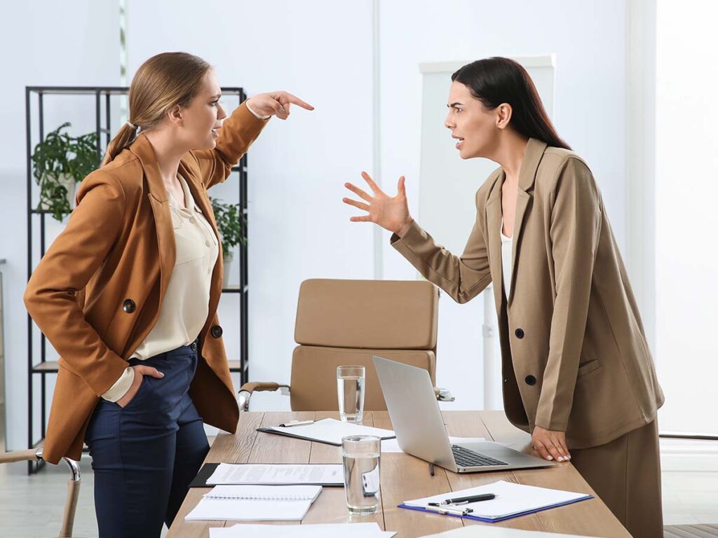 Zwei Frauen streiten sich im Büro, Konfliktlösung, Kommunikation, Business-Meeting, Spannungen, diskutieren am Tisch.