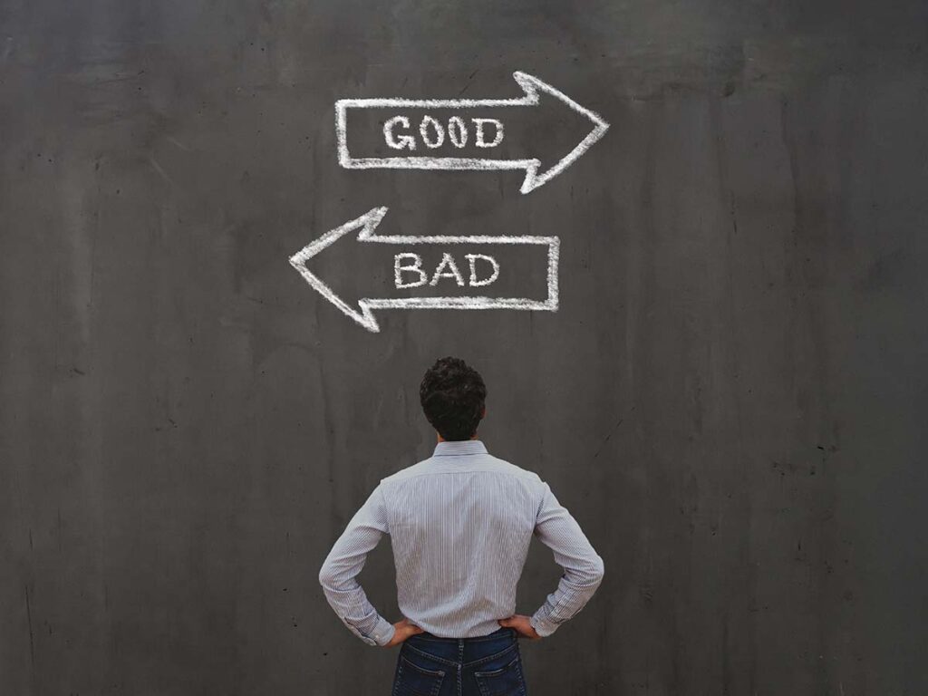 Mann wählt zwischen gut und schlecht auf Tafel. Entscheidungstreffen, Karriereweg, Orientierung, Zukunftsplanung.