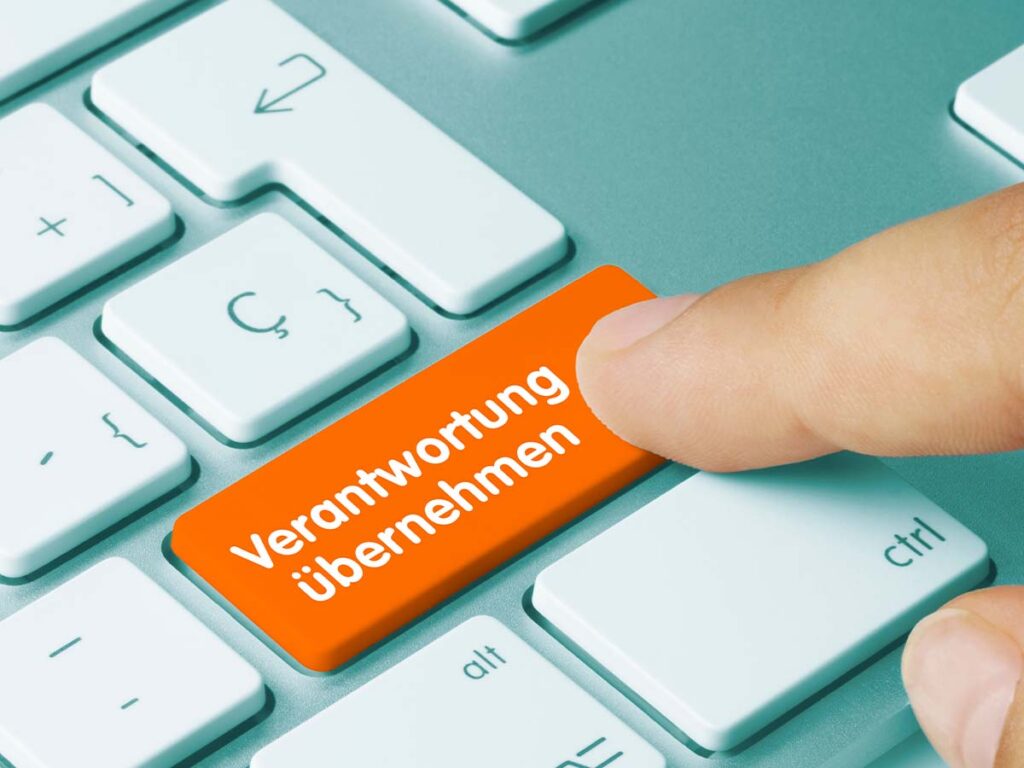 Finger drückt orange Verantwortung übernehmen-Taste auf Tastatur, symbolisiert Engagement und Verantwortung in Unternehmen.