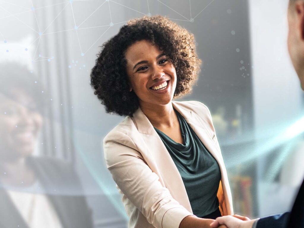 Unternehmerin mit lockigem Haar lächelt und gibt die Hand, Geschäftstreffen, freundlich, professionell, Bürohintergrund.