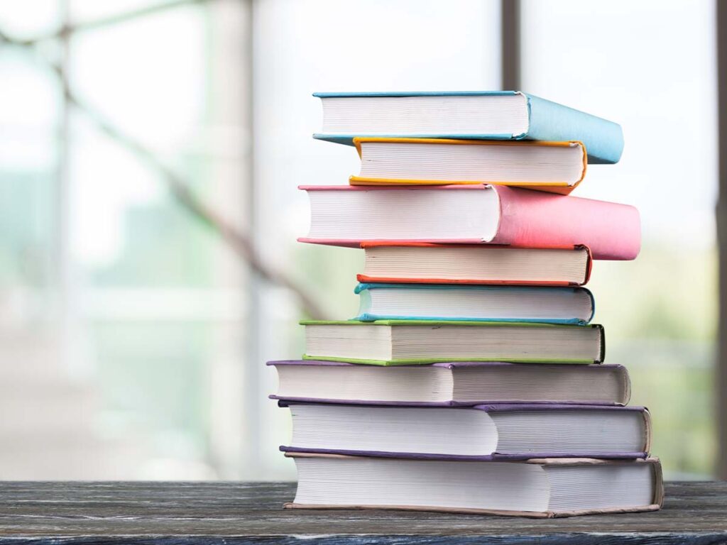 Stapel bunter Bücher auf Holztisch im Büro, ideal für Bildung, Lernen und Wissen. Bücherstapel, Bildung.