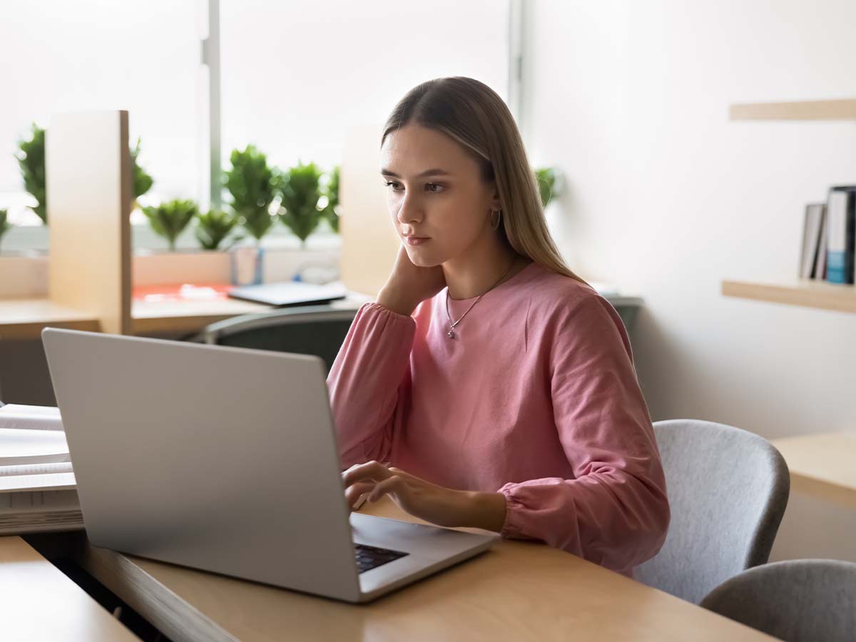 Eine Frau sitzt nachdenklich vor ihrem Laptop, während sie über die korrekte Verwendung des Verbs „zuschicken“ nachliest, um Missverständnisse in der digitalen Kommunikation zu vermeiden.