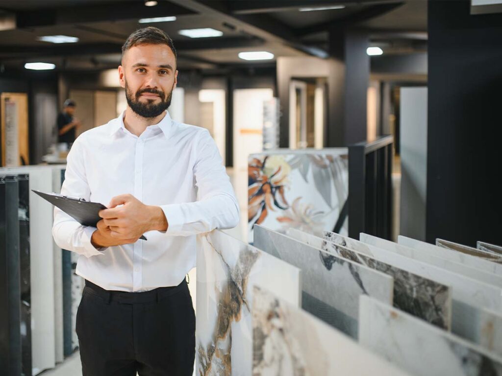Ein Verkäufer, Mann im Vordergrund, stützt sich auf Bildern ab und sucht einen Kunden für ein Verkaufsgespräch.